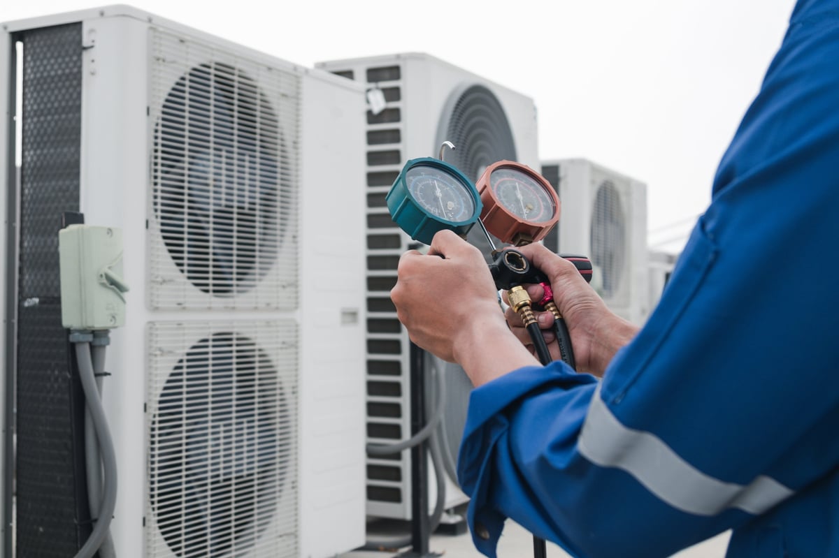 Technician measuring refrigerant while servicing an air conditioner