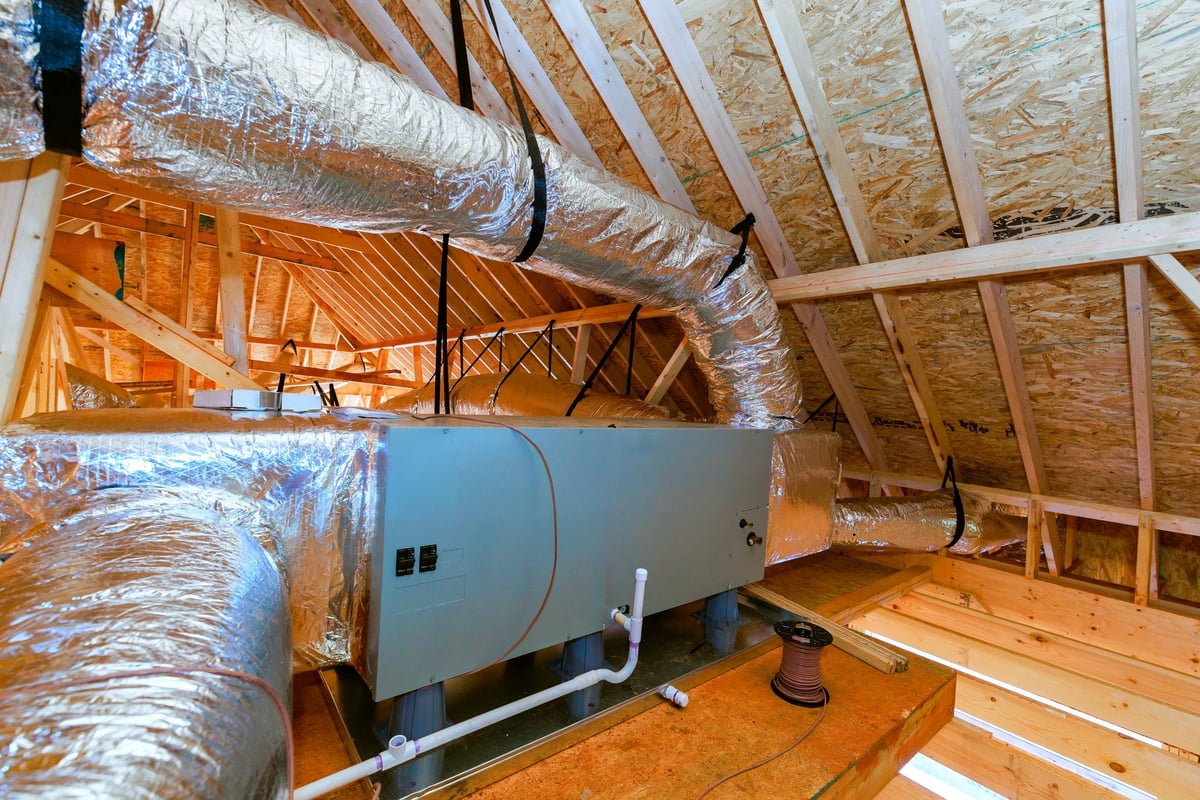 Workers installing a heating and cooling system in a home attic